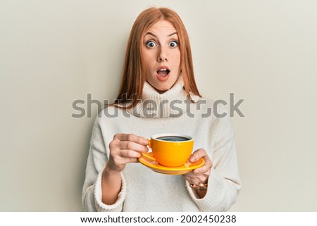 Young irish woman drinking a cup of coffee afraid and shocked with surprise and amazed expression, fear and excited face.  商業照片 © 