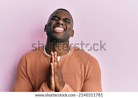 Young african american man wearing casual clothes begging and praying with hands together with hope expression on face very emotional and worried. begging.  商業照片 © 