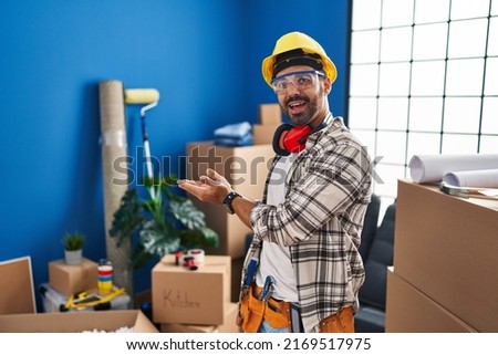 Young hispanic man with beard working at home renovation pointing aside with hands open palms showing copy space, presenting advertisement smiling excited happy  Foto stock © 