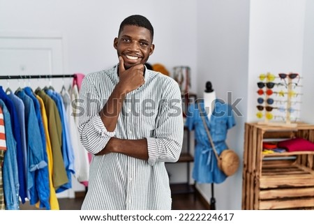Young african american man working as manager at retail boutique looking confident at the camera smiling with crossed arms and hand raised on chin. thinking positive.  Foto stock © 