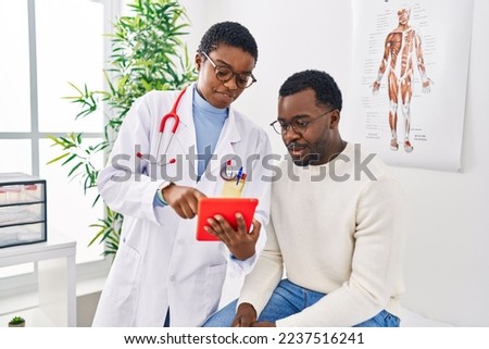 Man and woman doctor and patient having medical consultation using touchpad at clinic Foto stock © 