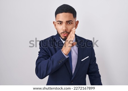 Young hispanic man wearing business suit and tie hand on mouth telling secret rumor, whispering malicious talk conversation  Foto stock © 