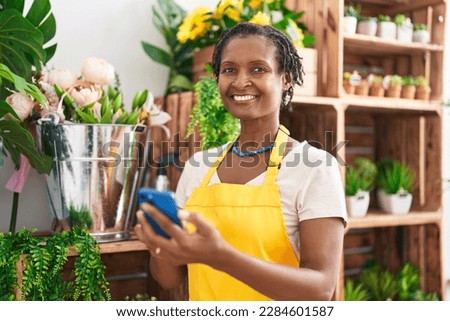 Middle age african american woman florist smiling confident using smartphone at flower shop Photo stock © 