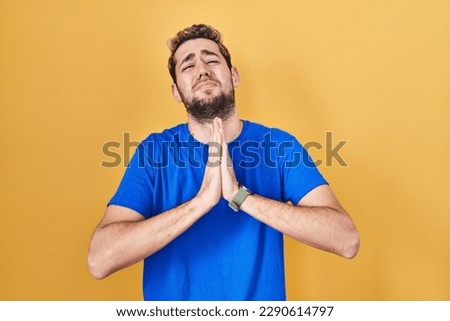 Hispanic man with beard standing over yellow background begging and praying with hands together with hope expression on face very emotional and worried. begging.  Сток-фото © 