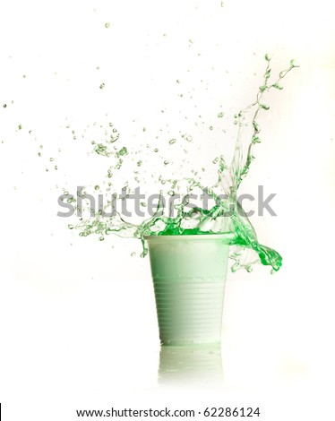 Green liquid splashing on plastic cup on white background