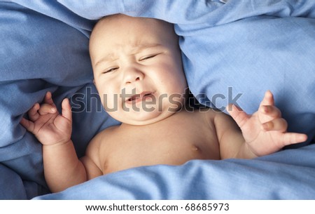 afraid baby under a blue blanket closeup