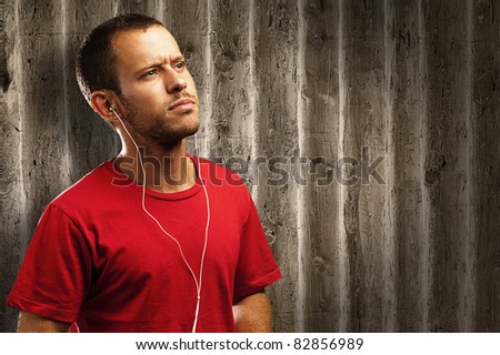 young man listen to music against a wooden wall