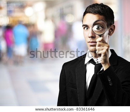portrait of handsome young man with magnifying glass in a shopping center