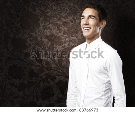 portrait of young man with white shirt smiling against a grunge background