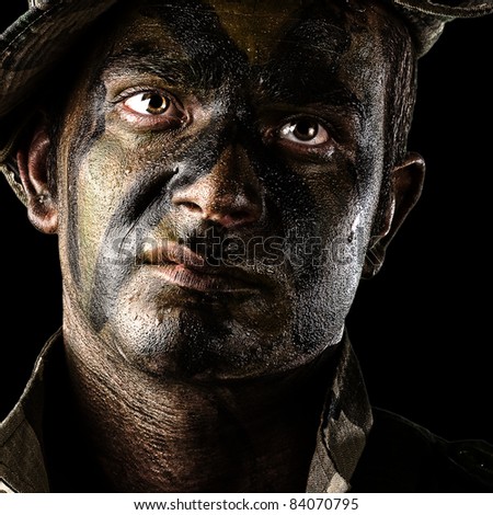 portrait of young soldier face with jungle camouflage over black background