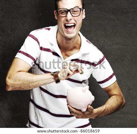 portrait of crazy man saving coins on piggy bank against a grunge wall
