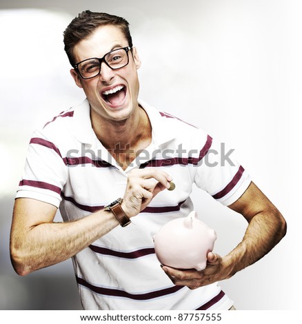 portrait of young man saving coins in piggy bank indoor
