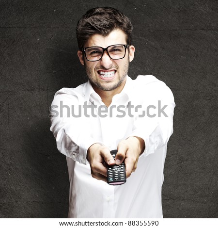 portrait of young angry man using remote control against a grunge background