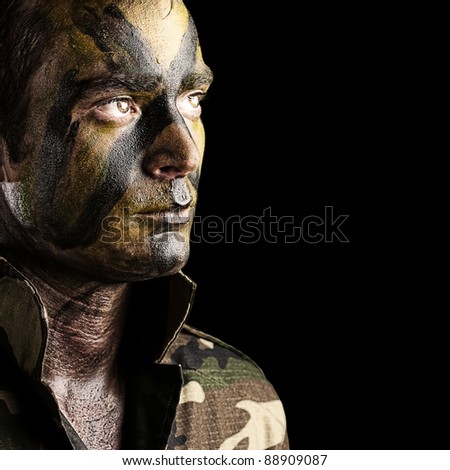 portrait of young soldier face with jungle camouflage against a black background