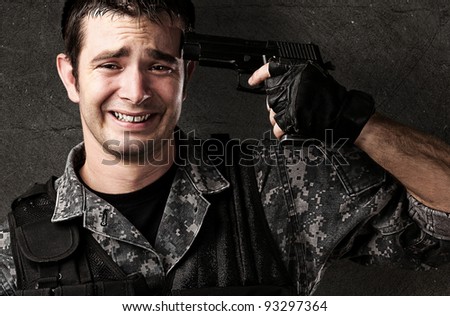 portrait of a young soldier committing suicide against a grunge wall