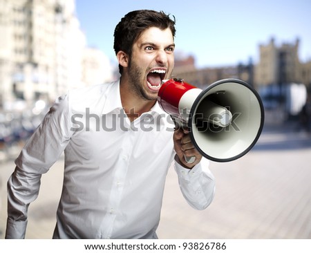 portrait of a man shouting with a megaphone against a street background