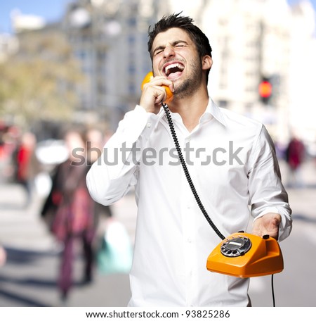 portrait of a young man talking on a vintage telephone at a street