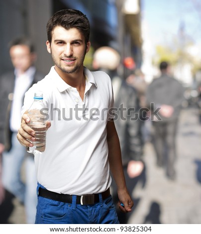 portrait of a young man offering water at a crowded street