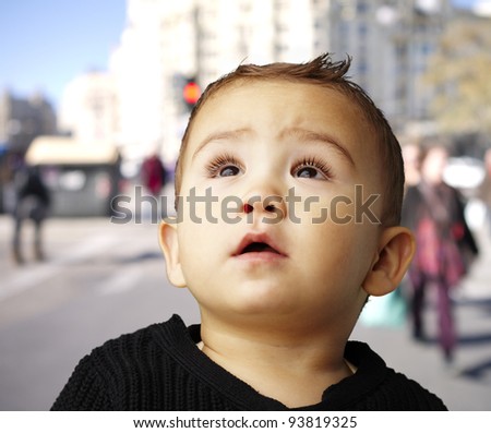 portrait of a handsome kid looking up against a crowded street