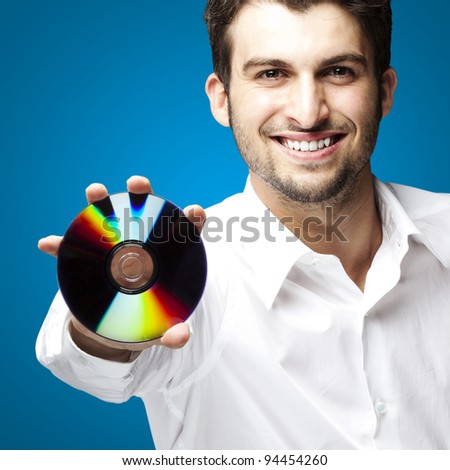 portrait of a handsome young man holding cd against a blue background