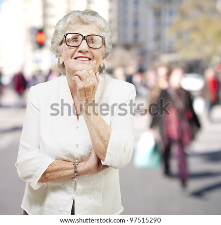 portrait of senior woman thinking and looking up at a crowded place