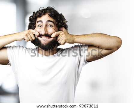 portrait of young man pulling his mouth smiling indoor