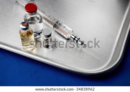 hypodermic needle and vials on stainless steel surface