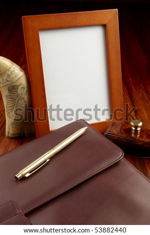 Blank frame, leather case, gold pen, scrimshaw whale\'s tooth and blotter shot on rosewood wooden desk