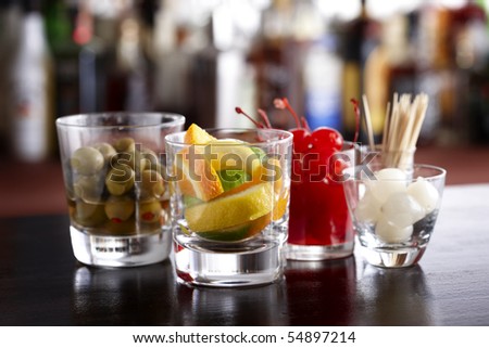 Several glasses filled with cocktail garnishes shot in a bar