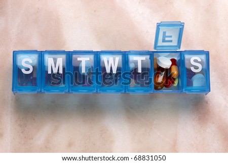 Blue plastic pill organizer shot on marble table with space for copy