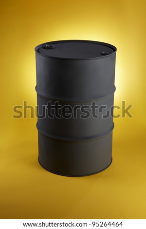 Black oil drum shot on bright yellow background with space for copy