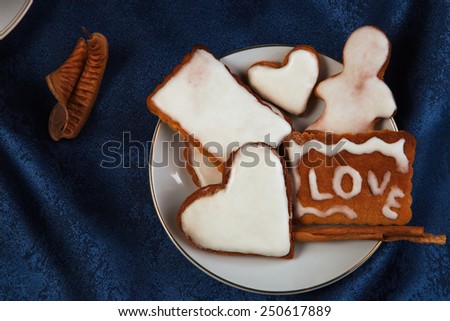 Ginger cookies with icing in the plate on a dark blue background with cinnamon sticks