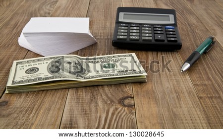 calculator, dollars, pen and paper on the table