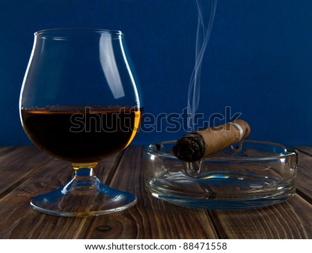glass with an alcohol and cigar on a blue background