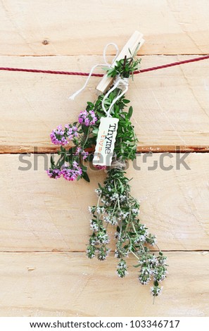 Bunch of fresh thyme with flowers and a name label hanging by a wooden peg against a wooden wall