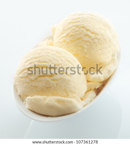 High angle view of scoops of creamy vanilla icecream served in a small white dish on a white background