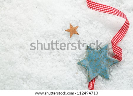 Christmas star background with a decorative red and white checked ribbon on a backdrop of winter snow with copysapce for your seasonal greetings