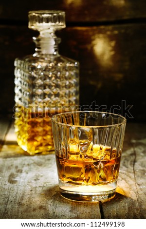Glass and bottle of hard liquor like scotch, bourbon, whiskey or brandy on wooden background with copyspace