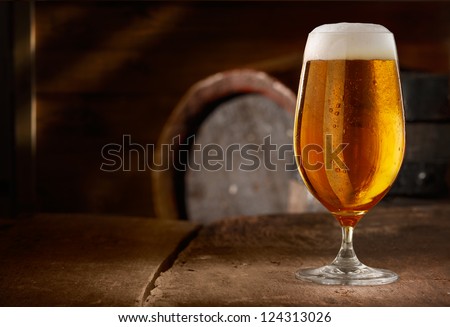 Closeup of a glass of fresh foamy beer on a table in a vintage beer cellar