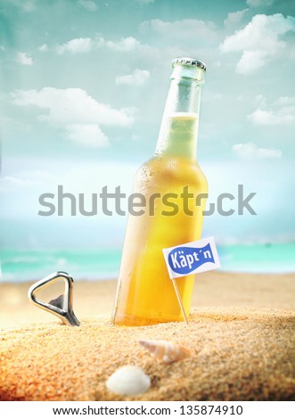 Beautiful photo of a chilled beer and a bottle opener on the beach tagged as Kapt'n. Stok fotoğraf © 