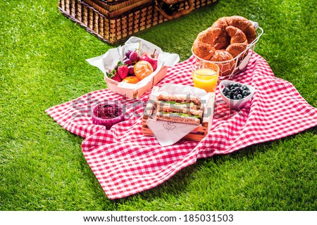 Healthy picnic for a summer vacation with freshly baked croissants, fresh fruit and fruit salad, sandwiches and a glass of refreshing orange juice laid out on a red and white checked cloth and hamper Foto stock © 