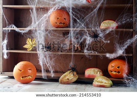 Halloween pantry with spider web covered shelves crawling with large black spiders and orange jack-o-lanterns with scary faces and a bat flying overhead