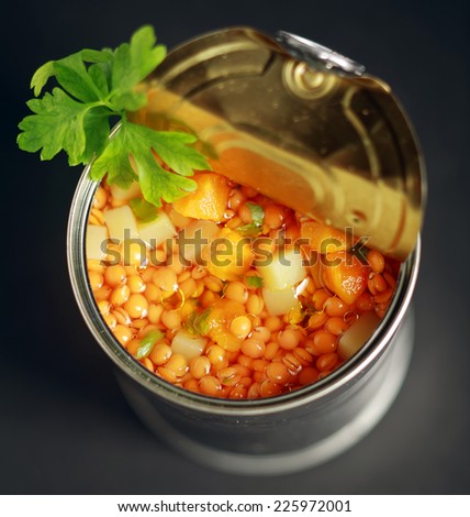 Close up view from above of an opened tin of canned lentil and mixed vegetable soup with diced carrot and potato garnished with fresh parsley