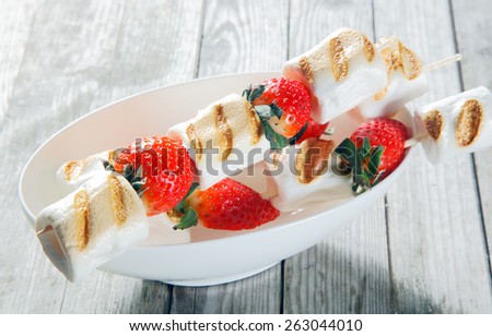 Close up Grilled Marshmallows and Strawberries on Sticks on Top of White Bowl, Placed on Rustic Wooden Table