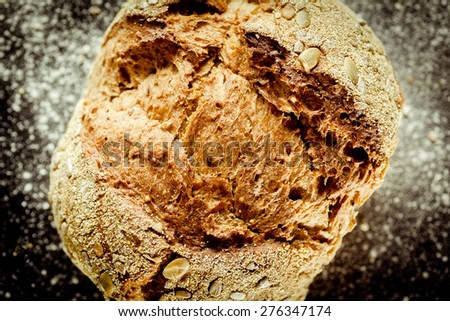 Rustic round traditional baked bread made of wheat flour with crispy crust and sunflower and pumpkin seeds, high-angle close-up