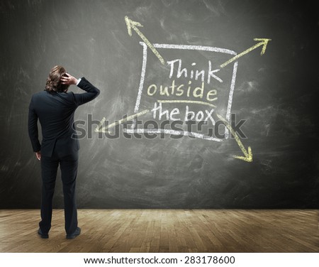 Rear View of Business Person Scratching Head with Hand in Confusion Standing in front of Chalkboard with Drawing Illustrating Creative Thinking - Think Outside the Box Concept