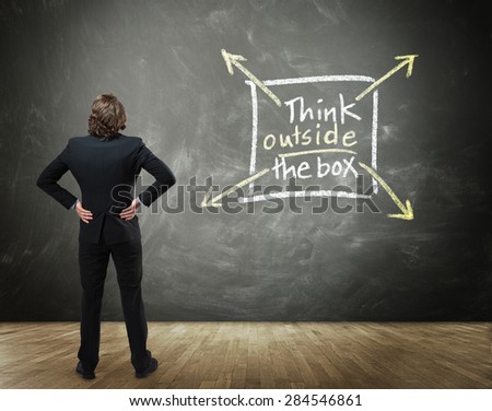 Rear View of Business Person with Hands on Hips Standing in front of Chalkboard with Drawing Illustrating Creative Thinking - Think Outside the Box Concept