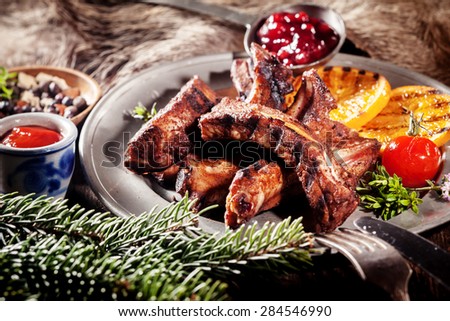 Appetizing BBQ Boar Spare Ribs with Grill Marks Served on Platter with Grilled Fruit and Sauces in Rustic Woodsy Still Life
