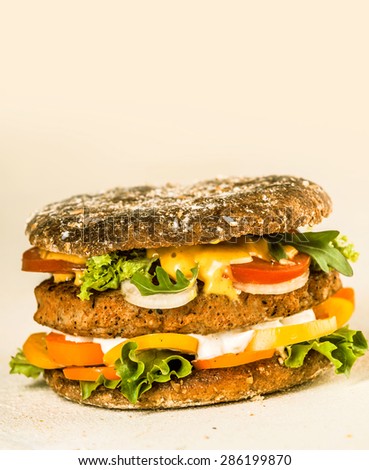 Close up Gourmet Tasty Hamburger with Fresh Veggies and Cheese on a Beige Background with Copy Space on the Top.