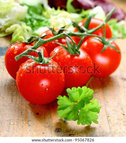 Bunch of fresh red ripe tomatoes with water droplets on rustic wooden boards.